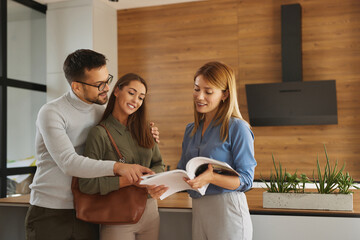 Female shop assistant helping young couple choose new kitchen appliance