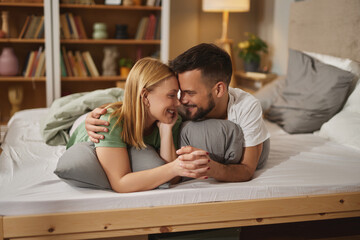 Affectionate young couple hugging and kissing in bed