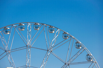 Big, tall white Ferris wheel in front of a perfect blue sky