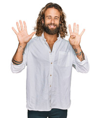Handsome man with beard and long hair wearing casual clothes showing and pointing up with fingers...