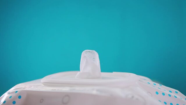 Taking a wet wipe from a package on a blue background. The concept of universal antibacterial viscose wipes for cleaning hands from bacteria and infections. Copy space for text. Slow motion, close-up