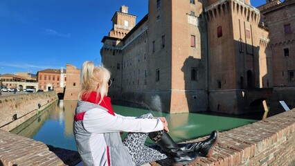 Tourist woman visiting the Ferrara castle of Italy. Surrounded by wide moat filled with water,...