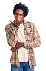 Handsome african american man with afro hair wearing casual clothes and glasses looking at the camera blowing a kiss with hand on air being lovely and sexy. love expression.