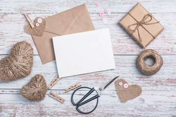 Craft envelope, blank form, heart shapes made of burlap and twine, scissors and a craft gift box on...