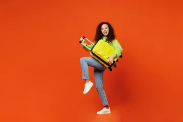 Foto op Canvas Full body traveler woman in casual clothes hold suitcase bag pov play guitar isolated on plain orange background Tourist travel abroad in free spare time rest getaway Air flight trip journey concept © ViDi Studio