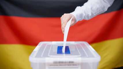 A German voter throwing a voting ballot into the sealed box, participating in elections in Germany