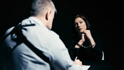 A male detective is writing down information during the interrogation of an arrested woman