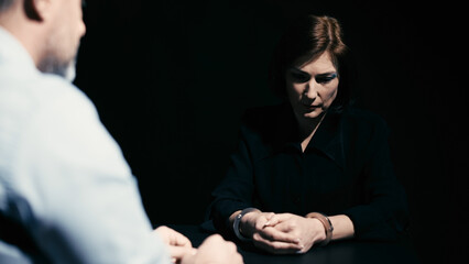 An arrested woman is attentively listening to the detective warning her of criminal liability
