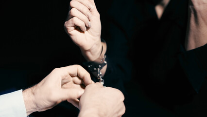 A policeman is removing handcuffs from a woman in custody, indicating charges dropped and freedom