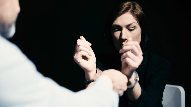 A police detective is uncuffing a woman in custody, indicating a wrongful arrest due to a lack of evidence