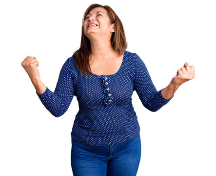Middle age latin woman wearing casual clothes very happy and excited doing winner gesture with arms raised, smiling and screaming for success. celebration concept.