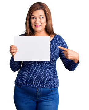 Middle age latin woman holding paper banner with blank space smiling happy pointing with hand and finger