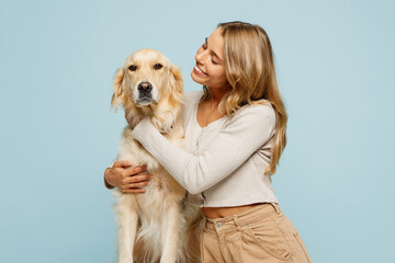 Young smiling lovely happy owner woman with her best friend retriever wearing casual clothes hug...