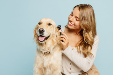 Young happy owner woman wear casual clothes hug cuddle best friend retriever dog hold grooming brush trimming isolated on plain pastel light blue background studio portrait Take care about pet concept