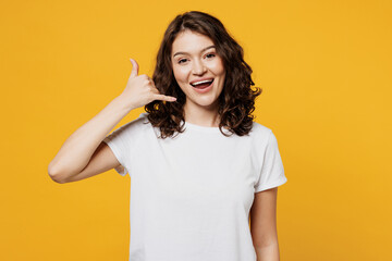 Young smiling cheerful Caucasian woman wear white blank t-shirt casual clothes doing phone gesture...