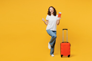 Traveler woman wear t-shirt casual clothes hold passport ticket bag isolated on plain yellow orange background. Tourist travel abroad in free spare time rest getaway. Air flight trip journey concept.