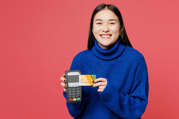 Young woman of Asian ethnicity wear blue sweater casual clothes hold wireless modern bank payment...