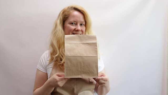 Woman seller holding kraft bag, meal delivery, market shopping, folded paper sack