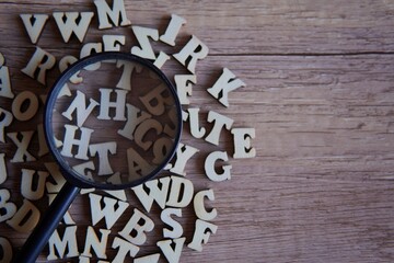Magnifying glass with scattered alphabet letters on the table. Copy space for text. Education...