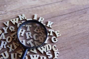 Magnifying glass with scattered alphabet letters on the table. Copy space for text. Education...