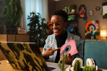 Young dark skinned afro american woman with short hair holding cd in hands doing paid advertisement...