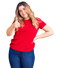 Young caucasian woman wearing casual clothes doing happy thumbs up gesture with hand. approving expression looking at the camera showing success.