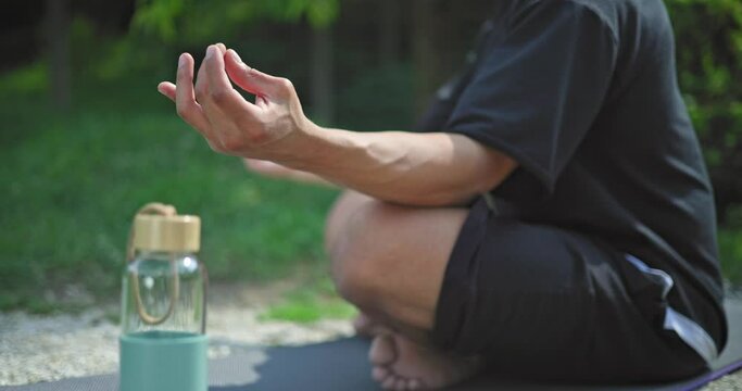 hands close-up - young african american spirituality man meditating yoga asana sitting in a park outdoor