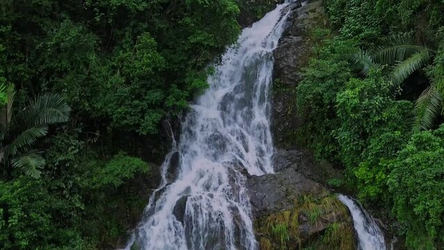 Waterfall flowing backwards on a cliff in the middle of a tropical forest with an aerial view from a drone. Backflow water effect.