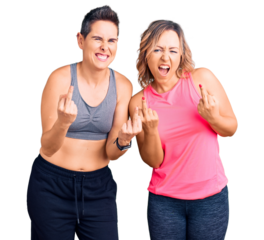 Couple of women wearing sportswear showing middle finger doing fuck you bad expression, provocation and rude attitude. screaming excited