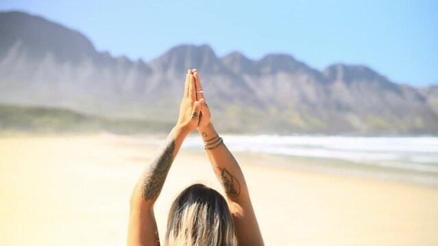 Person, meditation and praying hands by ocean for spiritual wellness, calm and peace in holistic practice. Back of yogi in yoga, palms together and mindfulness, faith and zen in nature or beach sand