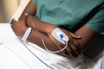 Close-up photo featuring an African woman's hands with an oximeter on her finger and a catheter...
