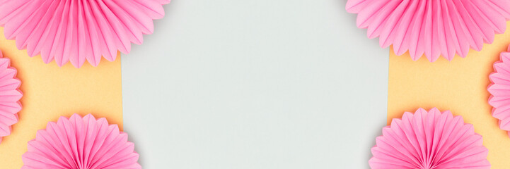 Banner with frame made of pink tissue paper fans on a blue background.