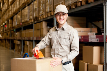 Male Chinese warehouse worker packing a box