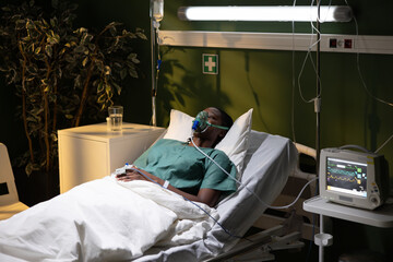 Photo of African patient, in hospital, with oxygen mask, lying down.