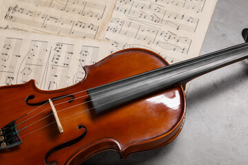 Violin and music sheets on grey table, closeup