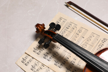 Violin, bow and music sheets on grey marble table. Space for text