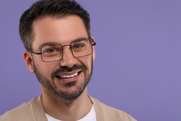 Portrait of happy man in stylish glasses on violet background, space for text