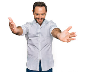 Fototapeta premium Middle age man wearing casual clothes looking at the camera smiling with open arms for hug. cheerful expression embracing happiness.