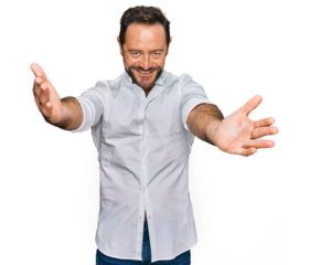 Middle age man wearing casual clothes looking at the camera smiling with open arms for hug. cheerful expression embracing happiness.