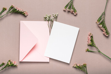 Pink envelope and blank form on a background of flowers. Greeting card, mockup.