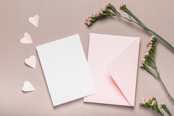 Pink envelope and blank form, pink flowers on a brown background. Paper pink hearts. Concept for Valentine's Day, Mother's Day.