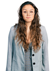 Young hispanic girl wearing business clothes and glasses puffing cheeks with funny face. mouth inflated with air, crazy expression.