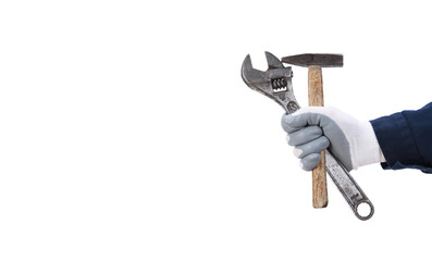 A worker's hand in a protective glove holds a large old adjustable wrench and a hammer on a white...