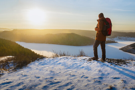 Man hiker hiking in winter. Traveler hiking in winter and enjoying mountains landscape at sunset. Freedom healthy lifestyle concept.
