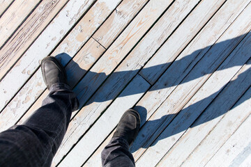 Shadow of a man's feet on a wooden floor