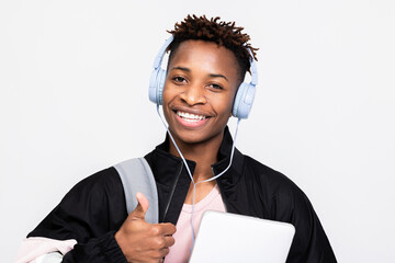 Portrait of delighted afro american dark skinned man wearing new wireless headphones listening to...