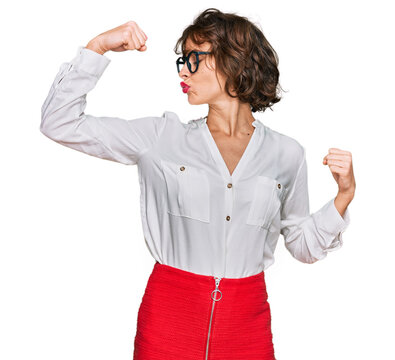 Young hispanic woman wearing business style and glasses showing arms muscles smiling proud. fitness concept.