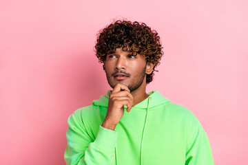 Portrait of indian young serious guy brainstorming touching chin pensive deep thinking look empty space isolated on pink color background