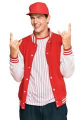 Handsome caucasian man wearing baseball uniform shouting with crazy expression doing rock symbol with hands up. music star. heavy concept.