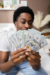 Handsome afr american dark skinned man holding money cash dollars in hands showing at camera high salary concept.